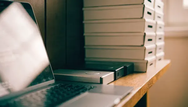 Discos duros externos y cajas de archivo etiquetadas sobre una estantería