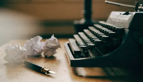 Máquina de escribir antigua junto a borradores de papel sobre un escritorio